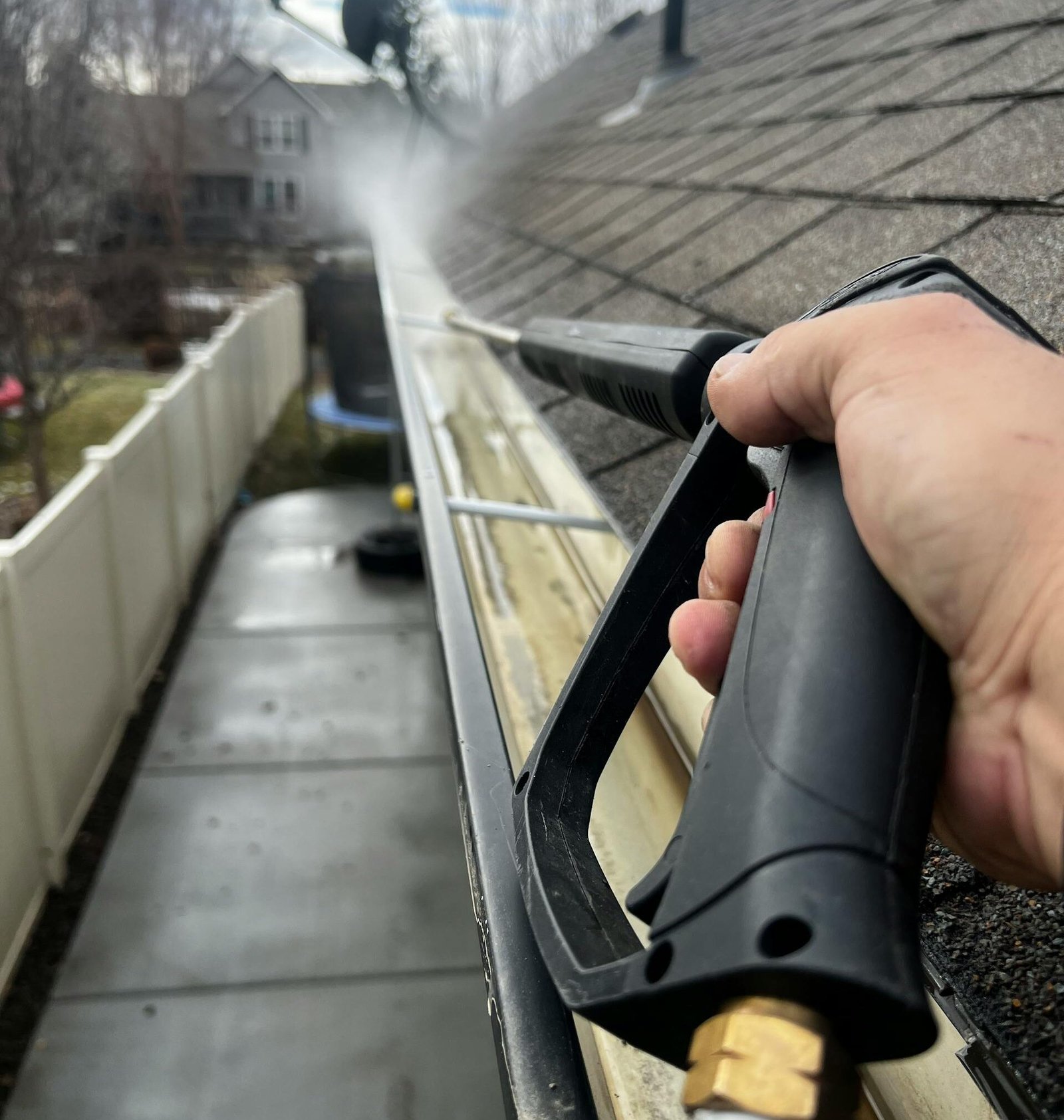 Close-up of gutter cleaning with pressure washer, outdoors, during the day.