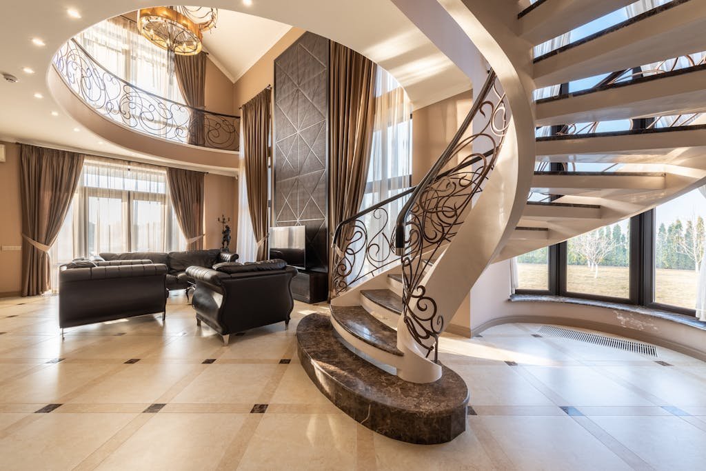 Spiral staircase with metal railings on tiled floor near comfortable leather couches placed in stylish spacious building with big windows